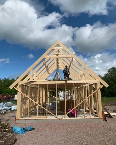 Pågående husbygge med husgrund av cement och plankor som formar väggar